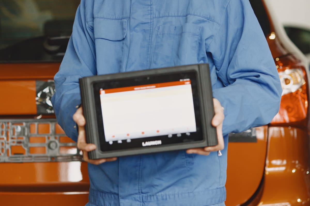Mechanic holding a diagnostic tablet with an out-of-focus display